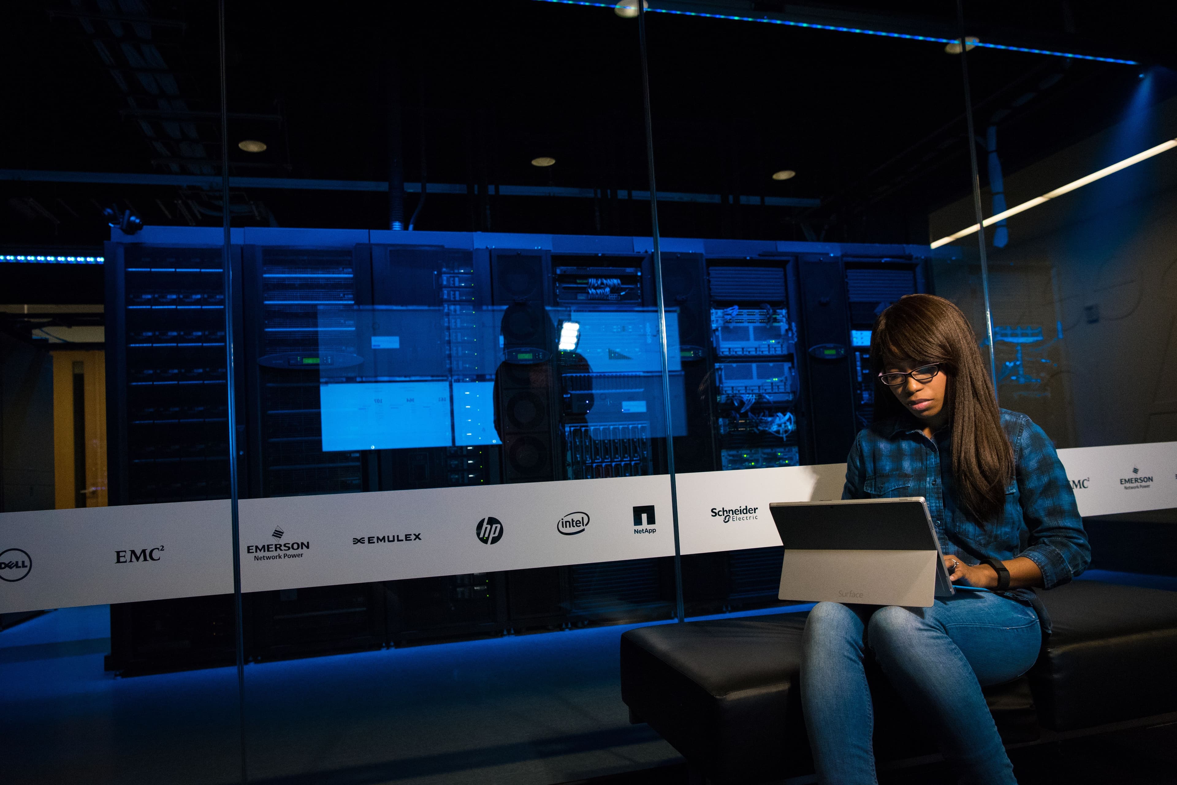 Woman using a laptop in a server room, showcasing modern technology and work environment